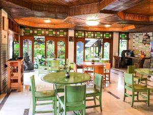 a dining room with tables and chairs and windows at Arys Garden Hotel Yogyakarta in Yogyakarta