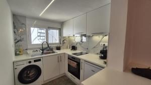 a kitchen with white cabinets and a washing machine at Alextina Residence in Artemida