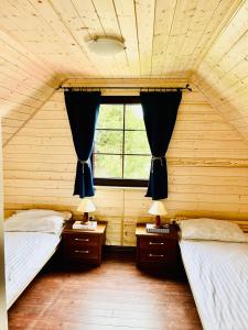 a bedroom with two twin beds and a window at Mazurska Chatka in Srokowo