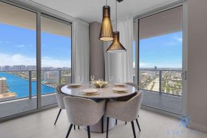 ein Esszimmer mit Tisch und Stühlen und großen Fenstern in der Unterkunft Luxury 3 Br - Corner Balcony - Panoramic View - Pools in Hollywood