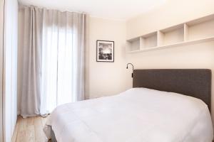 een slaapkamer met een wit bed en een raam bij Emerald Living Merlata in Pero