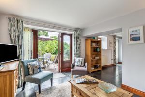 un soggiorno con televisione e tavolo di Petrock Holiday Cottages a Newton Saint Petrock