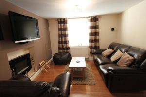 a living room with a leather couch and a television at Nairnia in Nairn