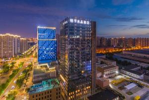 西安Xi 'an North Railway Station Municipal Government Orange Crystal Hotel的城市中一座亮着蓝色灯光的高楼