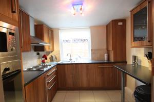 a kitchen with wooden cabinets and a sink and a window at Nairnia in Nairn