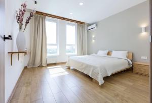 a white bedroom with a bed and a large window at 45 Kyiv Lovely Apartment in Nyvky Park in Kyiv