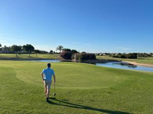mężczyzna spacerujący po polu golfowym z kijem w obiekcie Roda Golf & Beach Resort, Murcia w mieście Roda