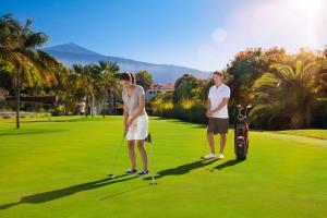 two men playing golf on a golf course at Hotel Botanico y Oriental Spa Garden in Puerto de la Cruz