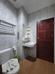 a bathroom with a toilet and a sink and a red door at New Forest Patong in Patong Beach