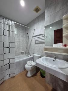 a bathroom with a toilet and a tub and a sink at New Forest Patong in Patong Beach