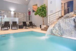 a swimming pool with a waterfall in a building at Le Clervaux Boutique Hotel & Spa in Clervaux