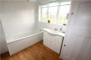 Un baño blanco con bañera y lavabo. en Charming family home in the heart of Sanderstead, en Purley