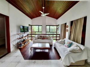 a living room with two couches and a tv at Pretty house with pool and amazing garden in São Sebastião