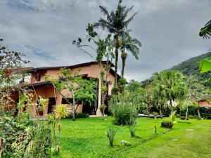 a house with palm trees in front of a yard at Pretty house with pool and amazing garden in São Sebastião