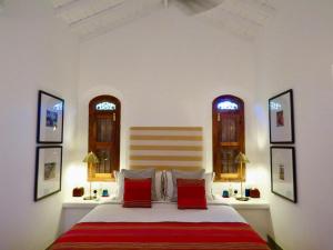 a bedroom with a bed with red pillows and two windows at Samaragiri in Talpe