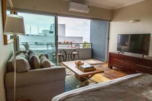 a living room with a couch and a television and a table at Clifton Beachfront Studio-Sea Views & Walk To Beach in Cape Town