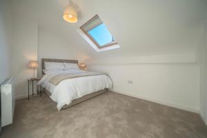 a white bedroom with a bed and a skylight at Kinsale Holiday Homes No2 Newmans Mall in Kinsale