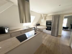 a kitchen with stainless steel appliances and wooden floors at Stilvolle Dachgeschosswohnung am Teutoburger Wald in Steinhagen +8 photos