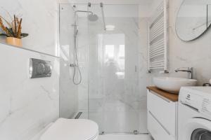 a bathroom with a shower and a toilet and a sink at APARTAMENTY MIERZEJA -TRIMARE, Sztutowo in Sztutowo +18 photos