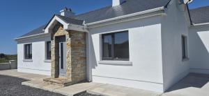 a white house with a brick pillar and a window at Innis Breeze - Between Murvagh & Rossnowlagh Beaches in Donegal