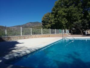 a swimming pool with blue water next to a fence at Dos casas rurales con piscina in Caravaca de la Cruz