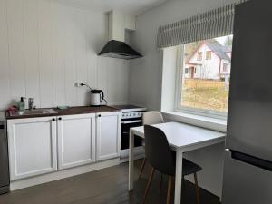 a kitchen with white cabinets and a table and a window at The Northern House in Gryllefjord
