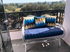 a chair with pillows on a balcony with a view at Blue Petals Homestays in Nanyuki