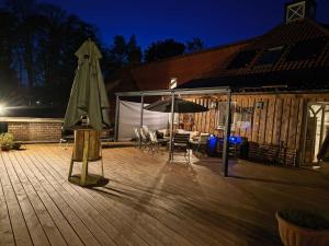 a wooden deck with an umbrella and chairs and a table at Casa Albers in Werlte