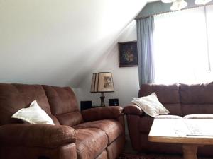 ein Wohnzimmer mit einem braunen Sofa und einem Tisch in der Unterkunft De Luxe - Ferienwohnung im Landhaus am See - Die Nr 1 mit 5 DTV zertifizierten Sternen in Malente