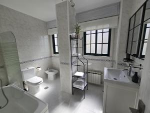 a bathroom with a toilet and a sink and a shelf at Winahost Salvora en Primera Línea de Mar in Ribeira