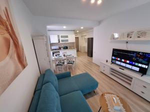 ein Wohnzimmer mit einem blauen Sofa und einem Fernseher in der Unterkunft SAB Apartament Mamaia Nord-Navodari in Mamaia Nord – Năvodari