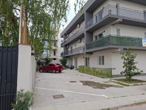 ein rotes Auto, das auf einem Parkplatz vor einem Gebäude parkt in der Unterkunft SAB Apartament Mamaia Nord-Navodari in Mamaia Nord – Năvodari