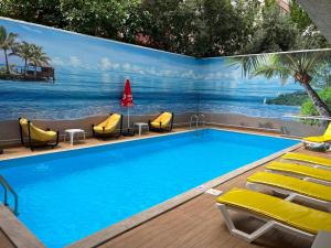 a swimming pool with chairs and a mural of the ocean at Old Town Point Hotel & Spa Antalya in Antalya