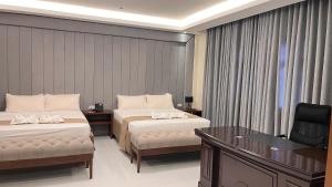 una habitación de hotel con dos camas y un escritorio en Pedro's Hotel, en Sorsogon