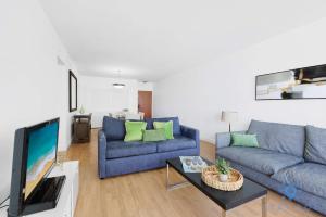 a living room with a blue couch and a tv at Tides beautiful ocean view condo-promotions in Hollywood