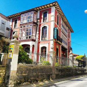 un edificio rojo y blanco al lado de una calle en Albergue La Casona Del Peregrino, en Llanes