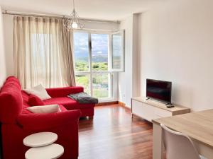 a living room with a red couch and a television at Apartamento La Cala Cuchía - Monabri in Cuchia