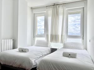 two beds in a room with two windows at Apartamento La Cala Cuchía - Monabri in Cuchia +24 photos