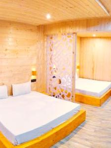 2 letti in una camera con pareti in legno di Hotel Mahadev a Badrīnāth