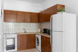 a kitchen with wooden cabinets and a white refrigerator at Aegean Breeze in Haraki