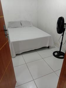 ein weißes Bett in einem weißen Zimmer mit einem Ventilator in der Unterkunft Recepções3d casa aconchegante com piscina in Campina Grande