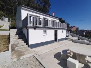 a white building with a balcony and a table at A Casa Pequena INCostadaMorte in Cee