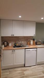 a kitchen with white cabinets and a sink at A Cozy Bothy Retreat with Hot Tub in Keilour