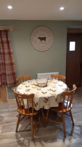 a dining room table with a white tablecloth with four chairs at A Cozy Bothy Retreat with Hot Tub in Keilour