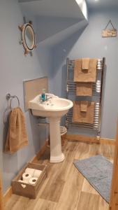 a bathroom with a sink and a mirror and towels at A Cozy Bothy Retreat with Hot Tub in Keilour
