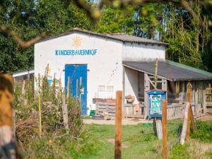 a white building with a blue door in a yard at Biohof Medewege in Schwerin