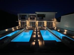 a villa with a swimming pool at night at Skopelos Holidays Hotel & Spa in Skopelos Town