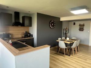 a kitchen and dining room with a table and a clock at Charmant appartement Cosy porte de Colmar in Sainte-Croix-en-Plaine
