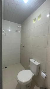 a white bathroom with a toilet and a shower at Vila Aconchego in Bragança