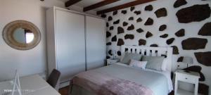 a bedroom with a bed and a wall covered in rocks at Casa Pilmar in Las Rosas